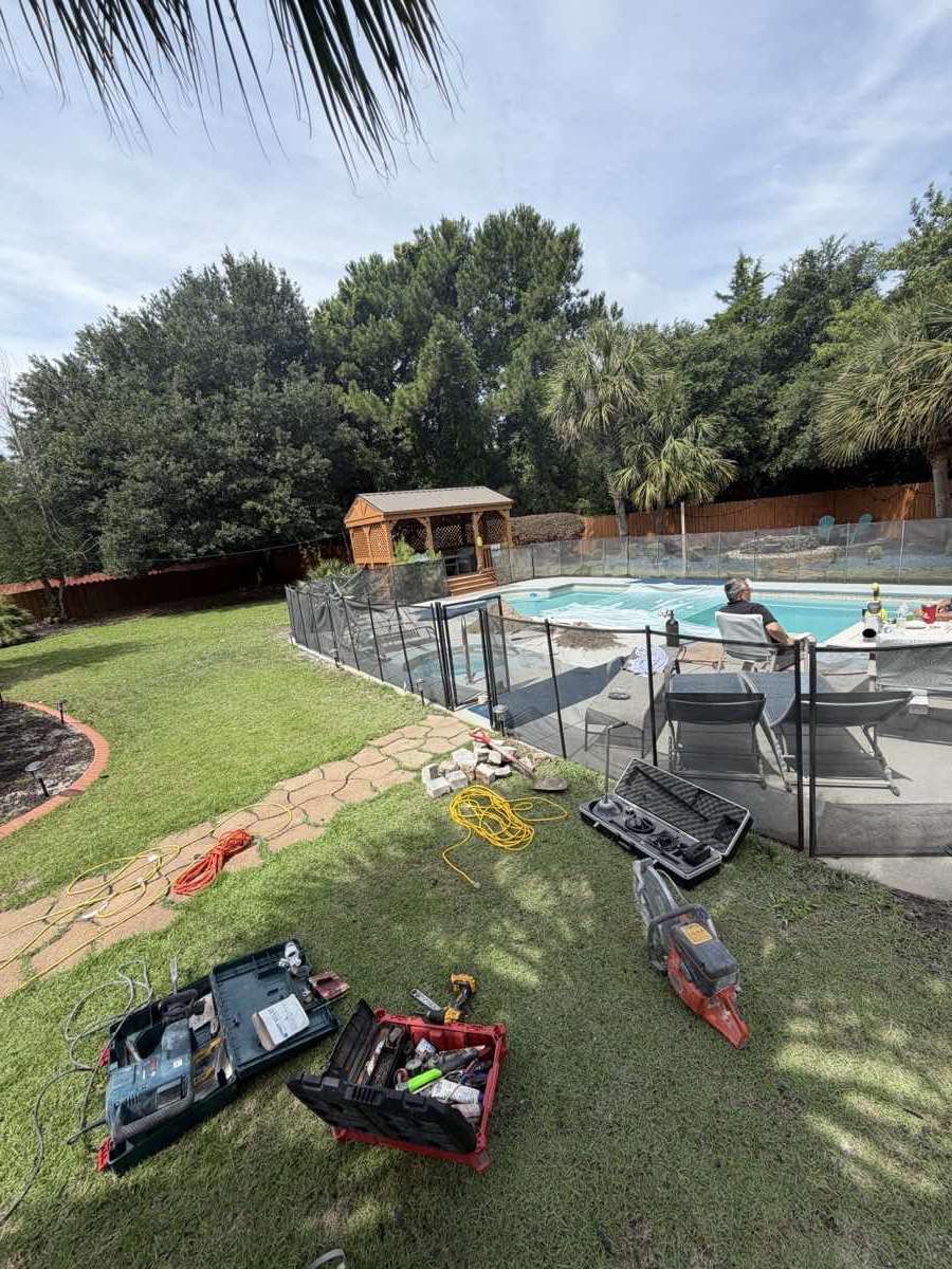 Tool cases open on grass beside a screened pool enclosure, with hoses coiled and a saw set down