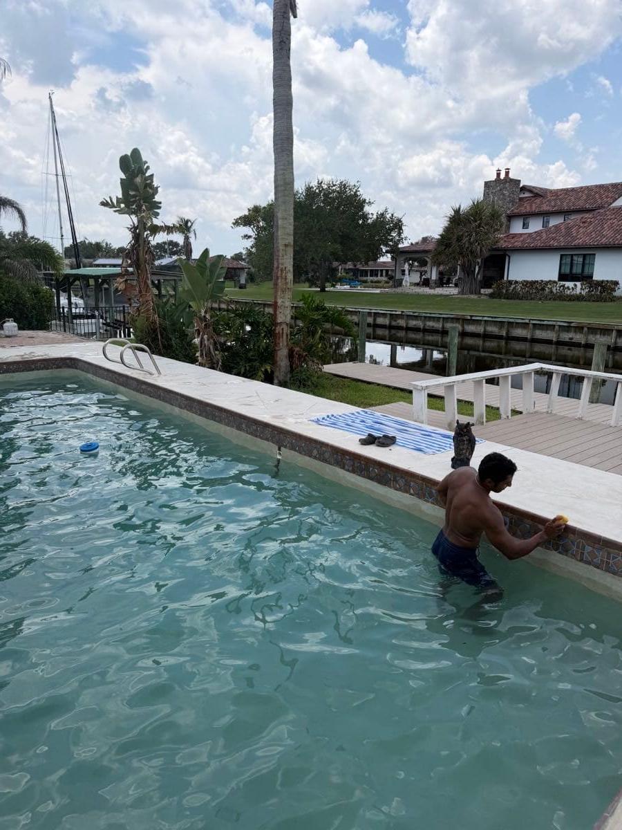J.R. Reyes waist-deep in a pool, working on the tile line by hand