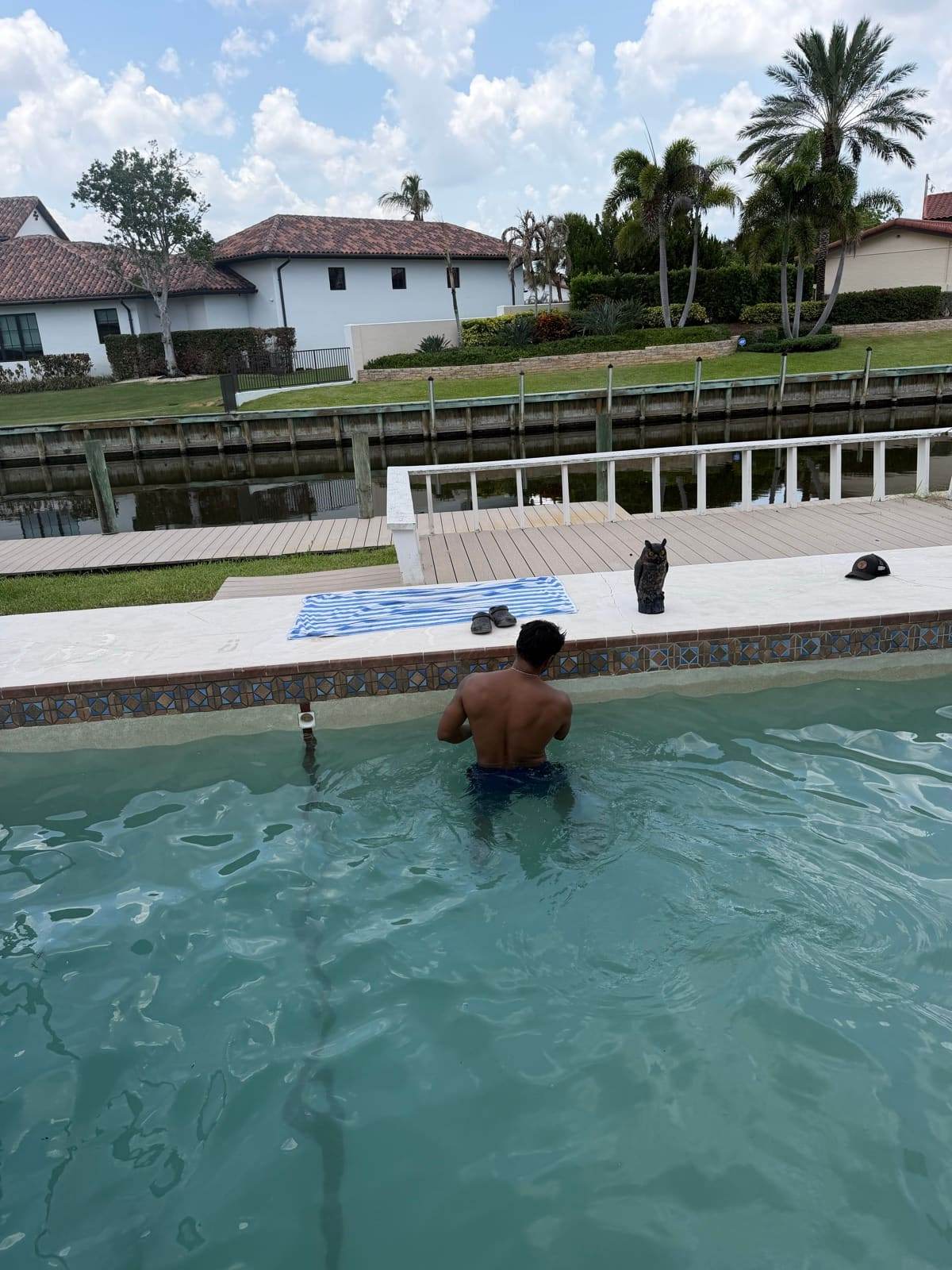 A technician working chest-deep at the tile line of a canal-front pool
